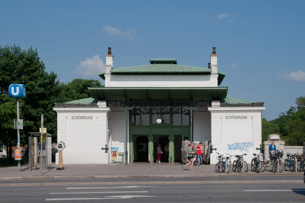 Das weiß-grüne Eingangsgebäude der U-Bahn-Station Schönbrunn, mit dem Stationsnamen an beiden Seitenwänden und davor abgestellten Fahrrädern
